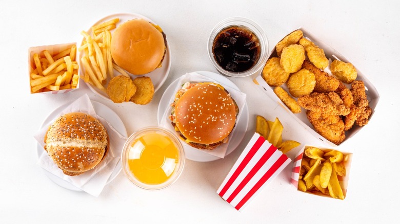 Fast food delivery menu background with various burgers, cheeseburger, nuggets, french fries, fizzy soda drinks