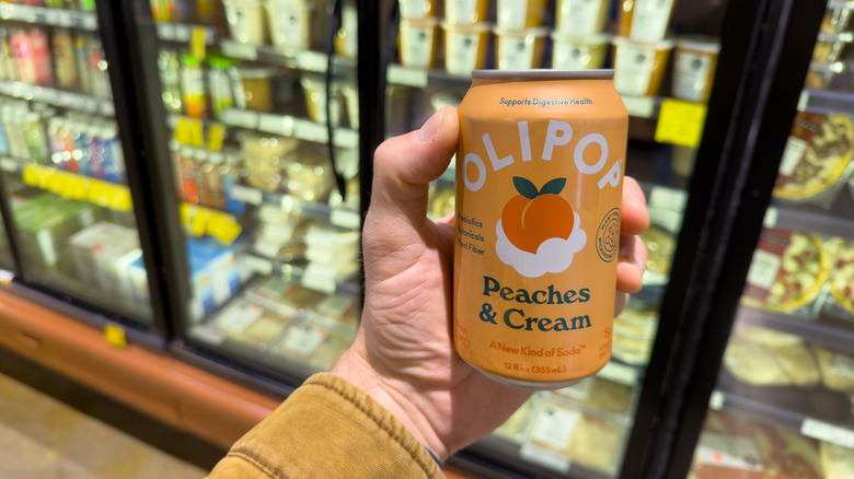 Hand holding can of Olipop in store