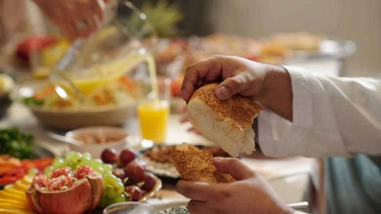 Hands Of Man Tearing Off Piece Of Bread During Dinner