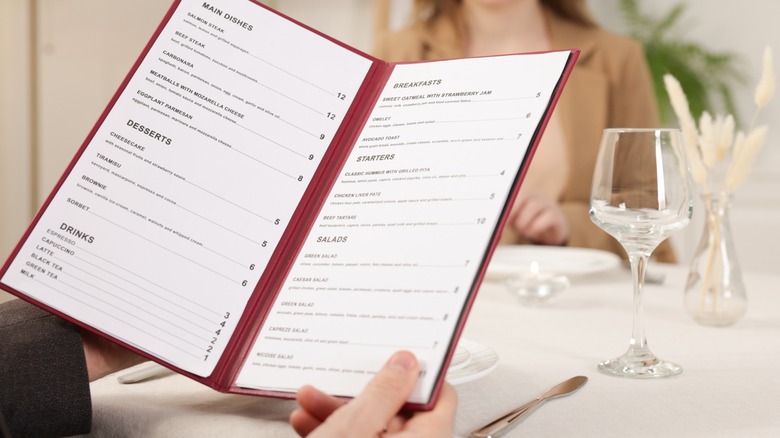 Man with menu at table in restaurant, closeup