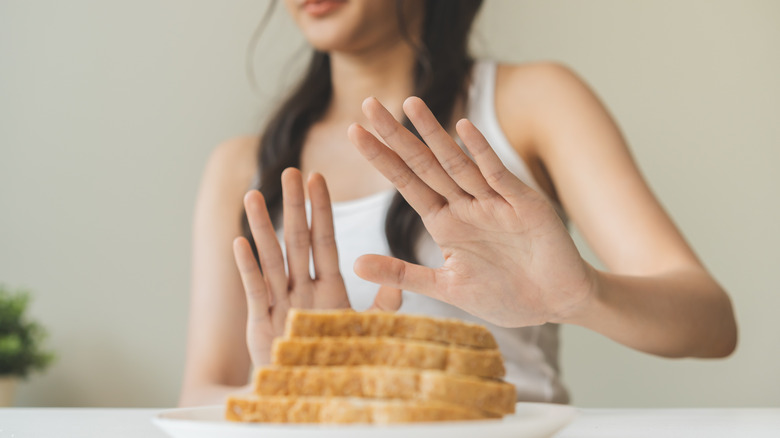 Woman putting hands out against plate of bread