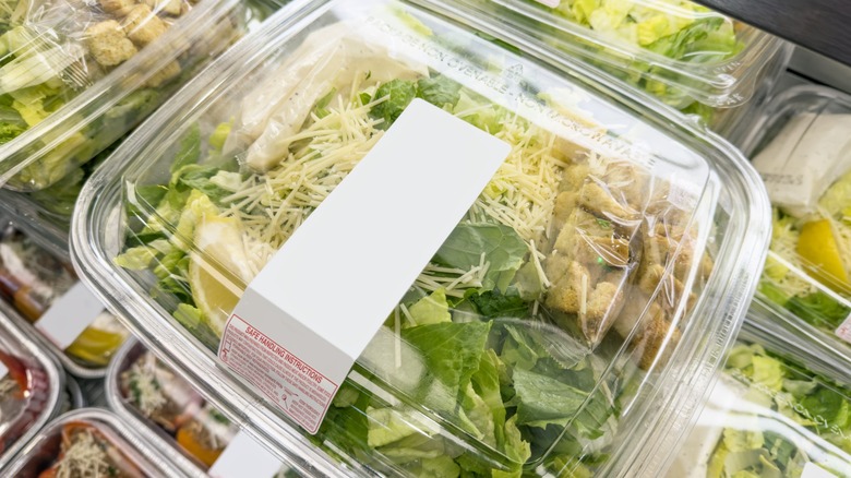 Boxes of premade salads stacked in a supermarket case