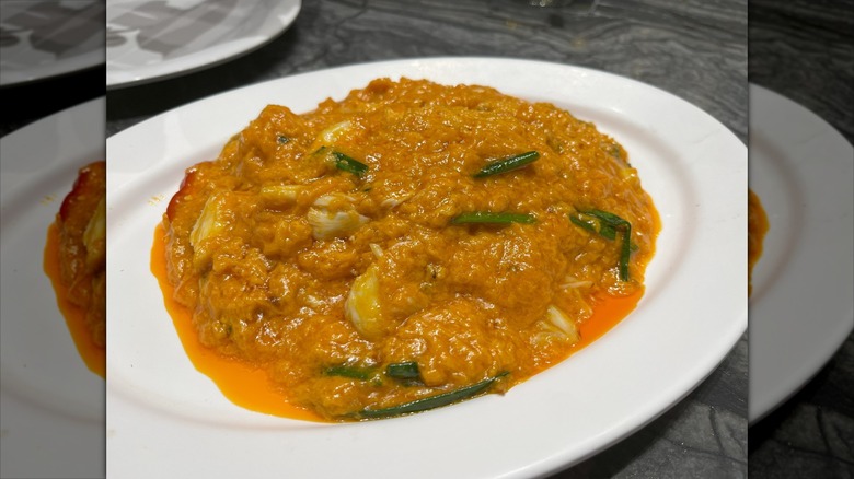 Authentic Thai Pu Pad Pong Curry made with fresh crab meat, eggs, and aromatic spices in a rich yellow curry sauce, served on a white plate with vibrant flavors and colorful presentation.