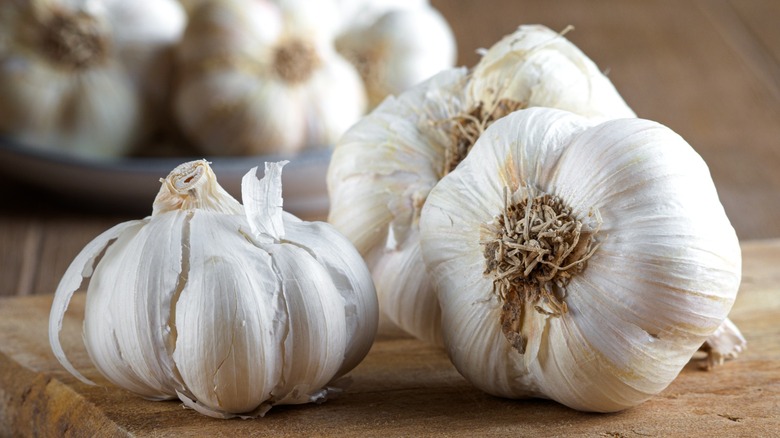Group of fresh organic garlic bulbs on wooden cutting board