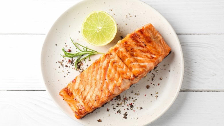 Grilled salmon fillet served on plate with slice of lemon