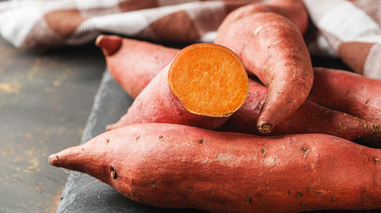 Sweet potatoes stacked on top of each other, one cut open