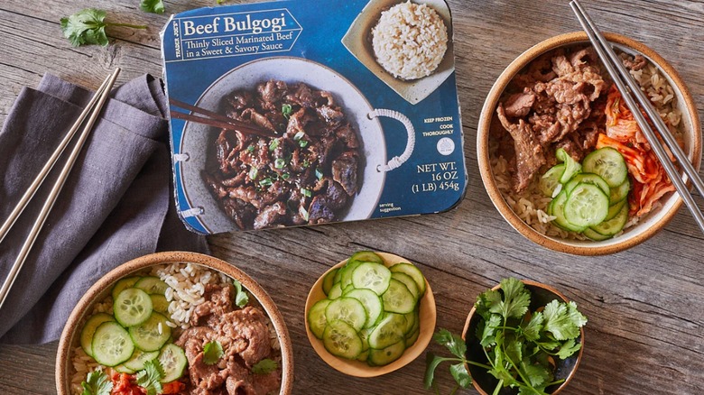 Trader Joe's Beef Bulgogi served in bowls with fresh veggies and chopsticks next to the packaging on a wood table