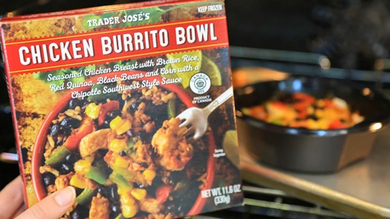 Trader Joe's Chicken Burrito Bowl packaging being held in front of food ready to eat