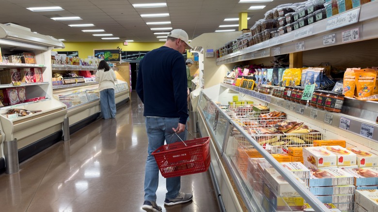 Male customer inside Trader Joe's Grocery store shopping for frozen meals in freezer aisle