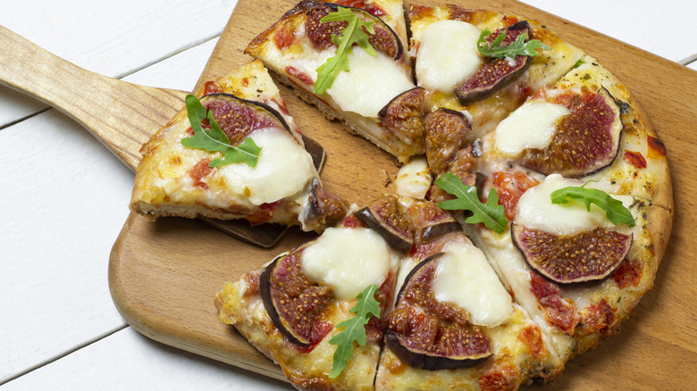 Fresh pizza with figs and mozzarella on a wooden board