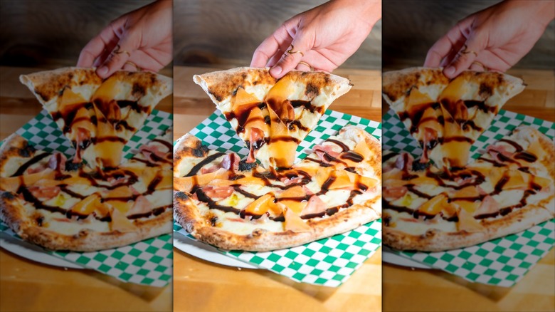 Melon Prosciutto Neapolitan Italian Pizza on checkered paper with a hand grabbing a slice