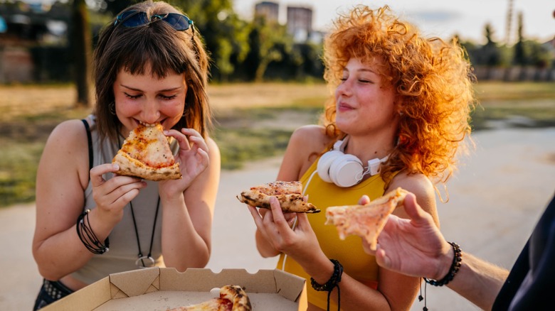 Two female friends enjoying pizza in a skate park