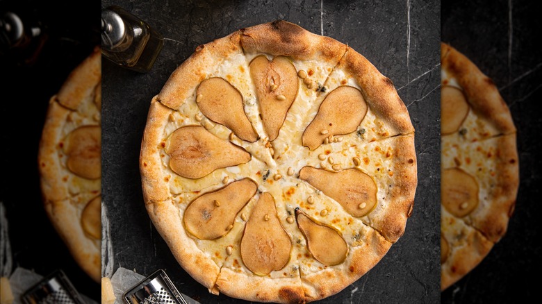 Gourmet pear and cheese pizza with crispy crust on dark background