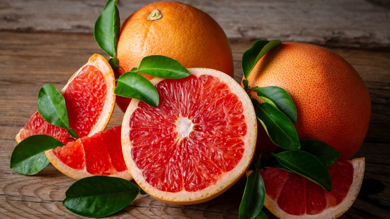 Grapefruits on a wooden table, some sliced in half, others whole
