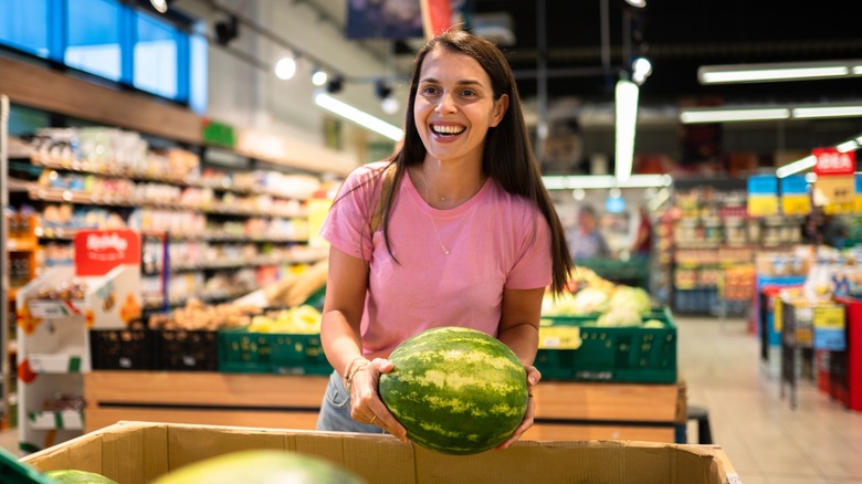Female shopper holding a watermelon in a supermarket grocery section