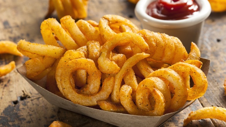 A serving of curly fries with ketchup.