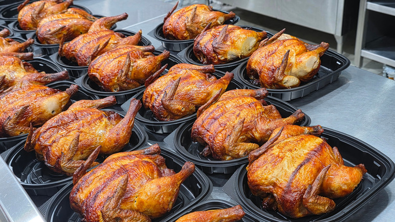 Rotisserie chickens in open black plastic containers