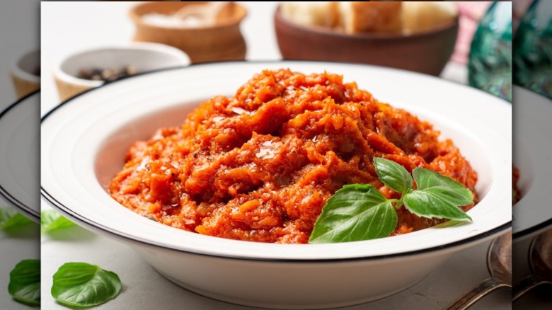 bowl of thick red soup made with tomatoes and stale bread with herb garnish