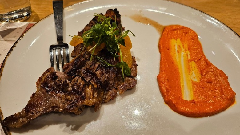 Steak with a red sauce on a white plate from Capa Steakhouse