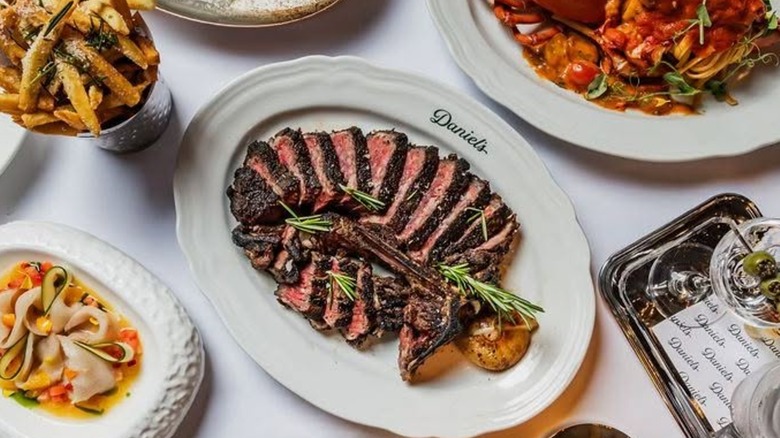Various dishes including French Fries and a sliced t-bone steak on a white platter from Daniel's Florida Steakhouse in Miami