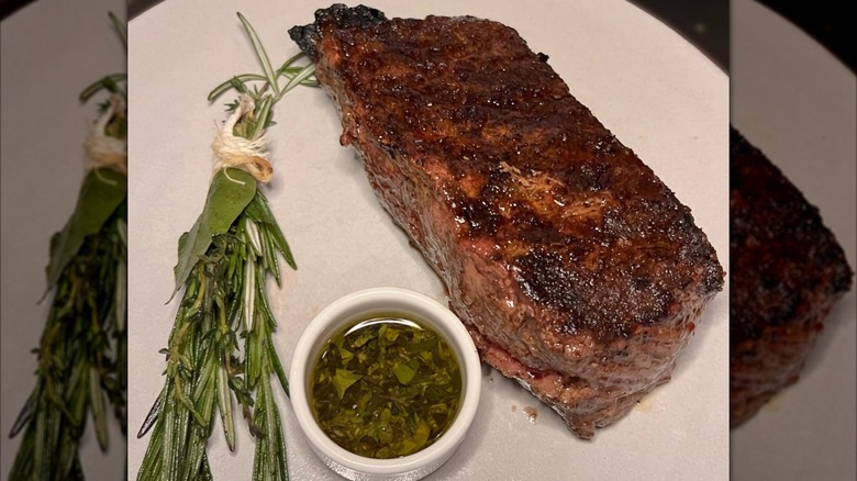 Steak with oil dish and herb satchet on side on a white plate at Nicholson Muir
