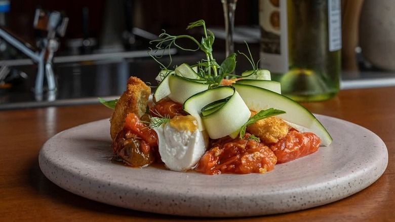Entree with curled Zucchini strips, tomato sauce, fresh cheese from Ossobuco on a white stone plate