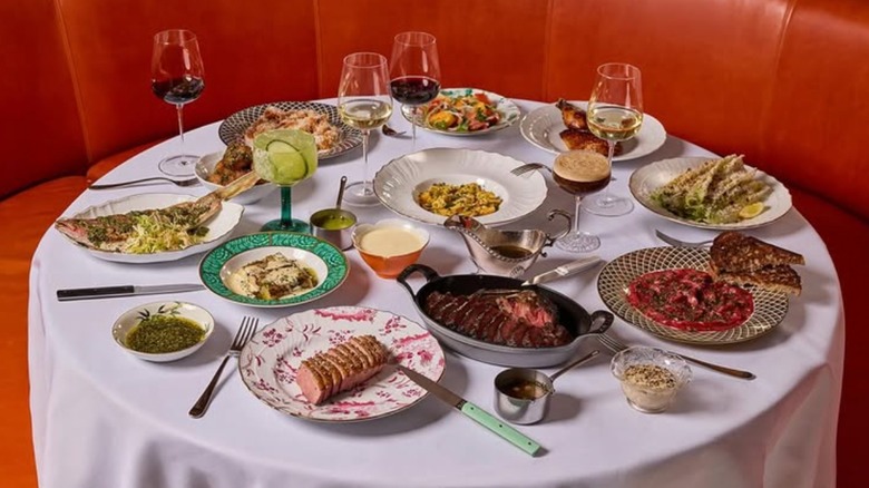 Various dishes including seafood, pasta, steaks, and glasses of wine on dining table with white tablecloth at Sunny's Steakhouse