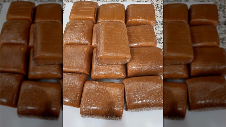 A pile of individually wrapped portions of kūlolo, Hawaiian taro pudding, on a counter top