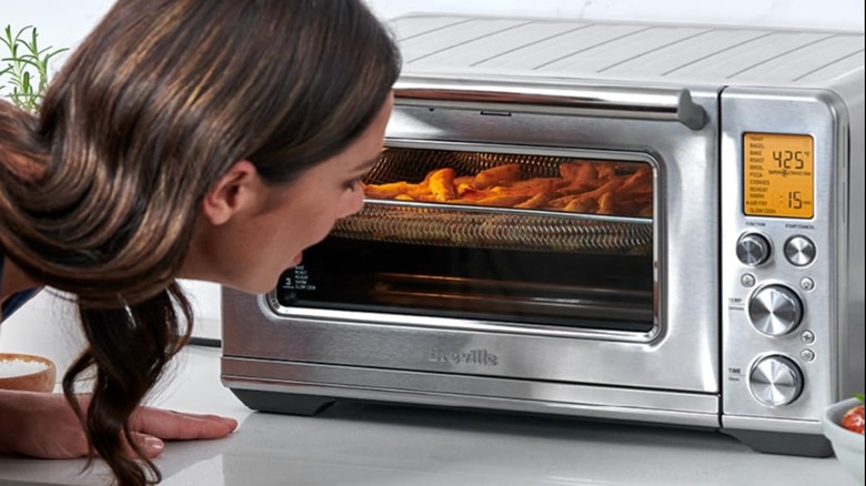 Woman looking at fries cook in a Breville Smart Oven Air Fryer Pro 