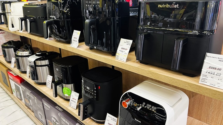 A variety of air fryers and kitchen appliances placed neatly on a retail shelf