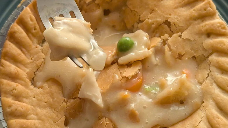 A closeup of a cooked Marie Collender's chicken pot pie, with a fork hovering overtop
