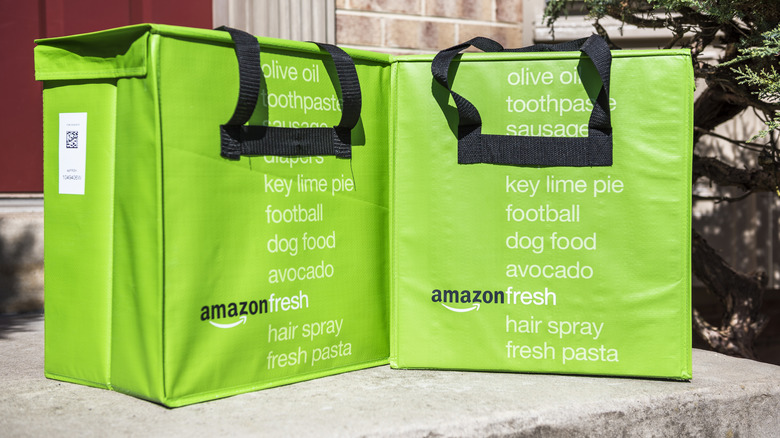 Two insulated lime green grocery bags from Amazon Fresh rest on a doorstep