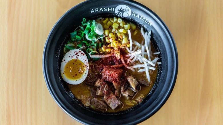 A black bowl of ramen with the Arashi Ramen logo on the side