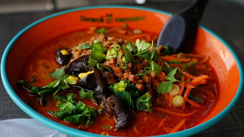 A bowl with the Gokoku Ramen logo filled with a spicy ramen and garnishes