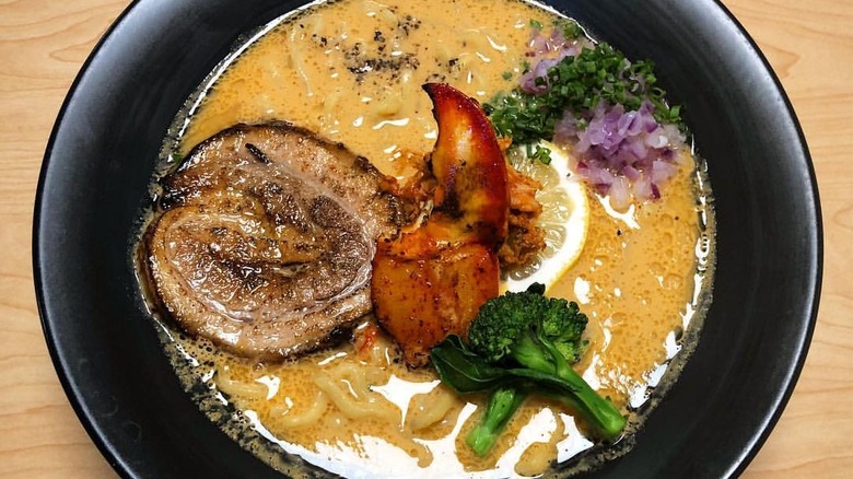 A black bowl of ramen with pork and seafood