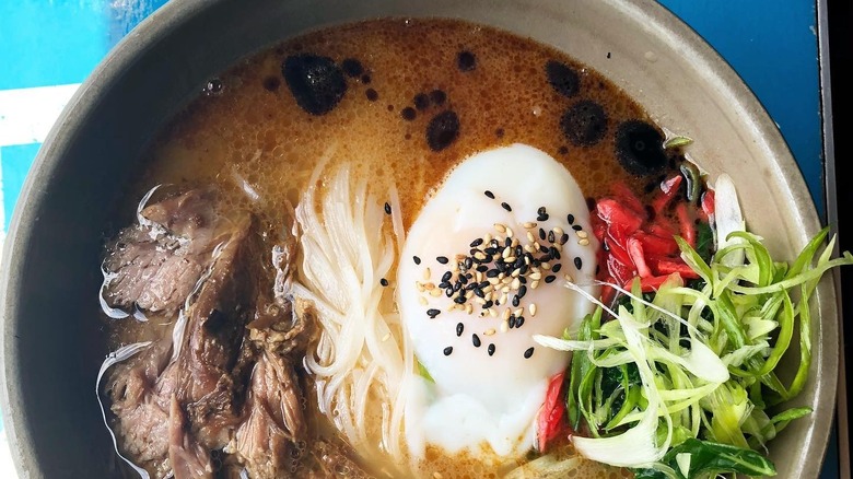 A close up of a bowl of ramen noodles, broth, and a soft boiled egg