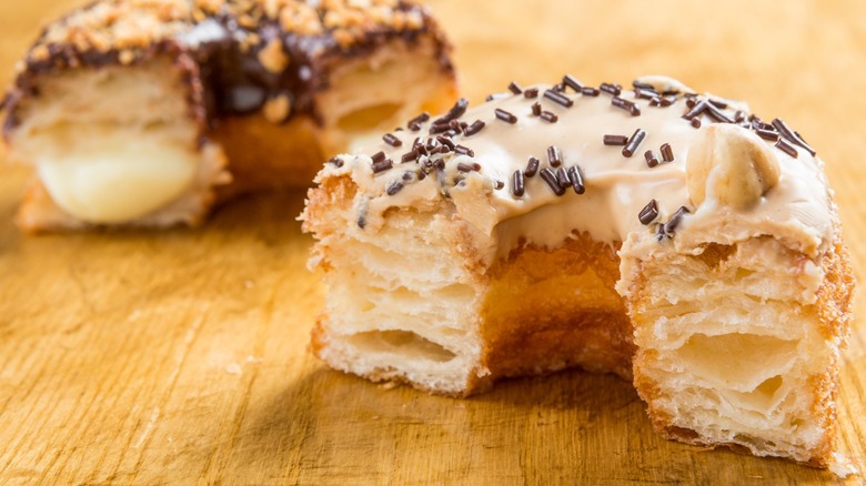 Chocolate and almond cronuts cut in half on a wooden table