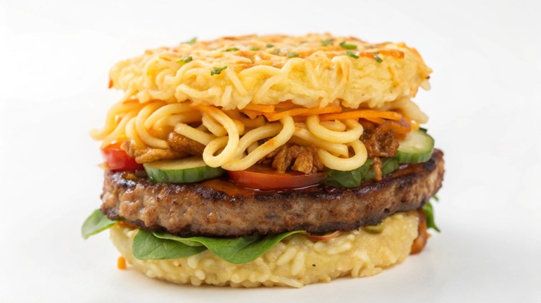 Ramen burger with a juicy meat patty, fresh vegetables, and ramen noodles as the bun