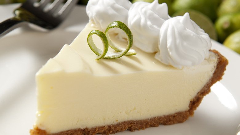 Slice of Key lime pie with whipped cream and lime rind
