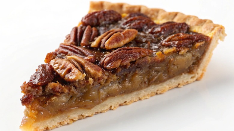 A slice of pecan pie on a white background