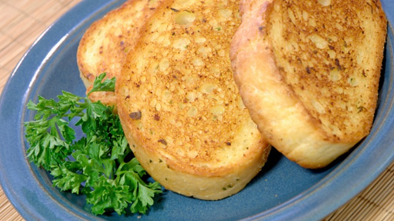 Three slices of Texas toast on a small blue ceramic plate garnished with parsley