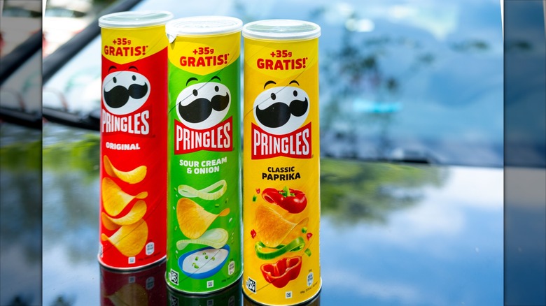 Three iconic Pringles cans on a reflective surface