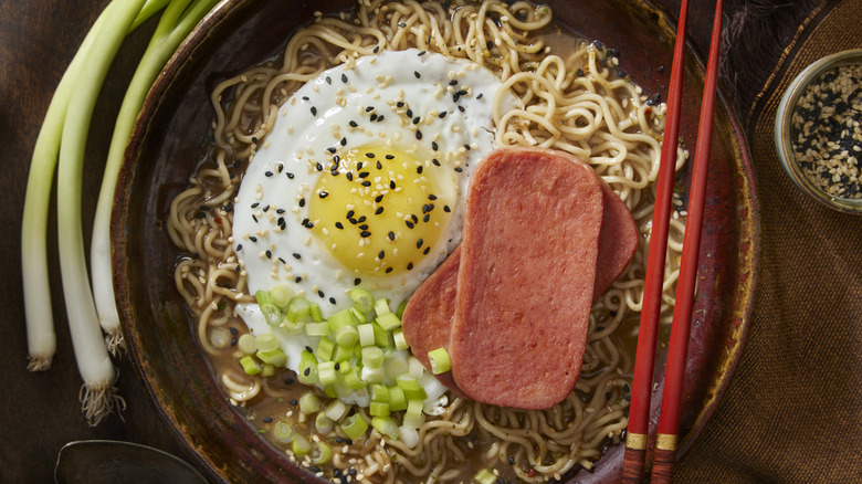 A bowl of sesame and SPAM ramen topped with an egg and scallions