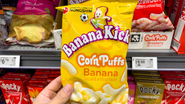 Hand holding bag of Banana Kick corn puffs