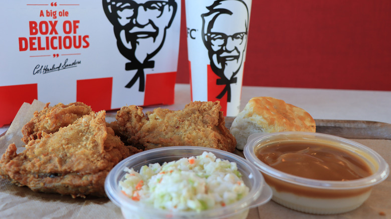 A spread of KFC chicken, with a container of coleslaw and container of gravy.