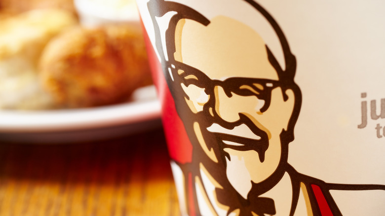 A close up of the Colonel Sanders image on a chicken bucket, the image behind blurred.