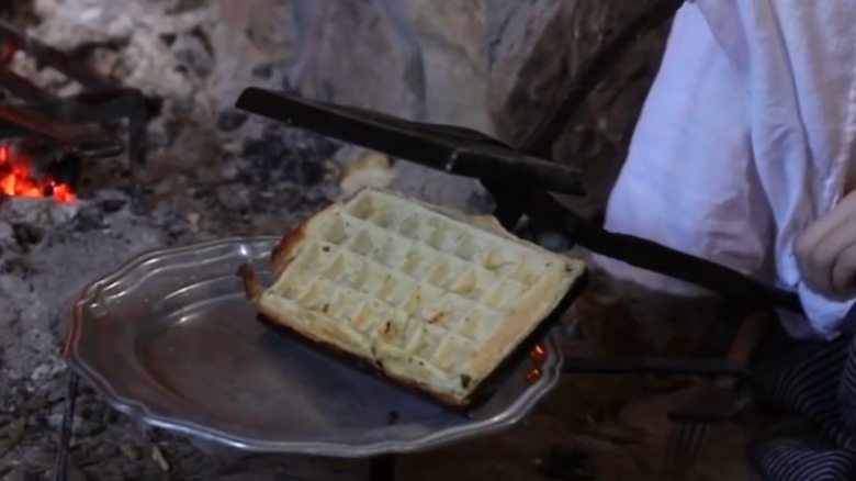 Woman's hands seen using Cast Iron Waffle Iron to make waffles