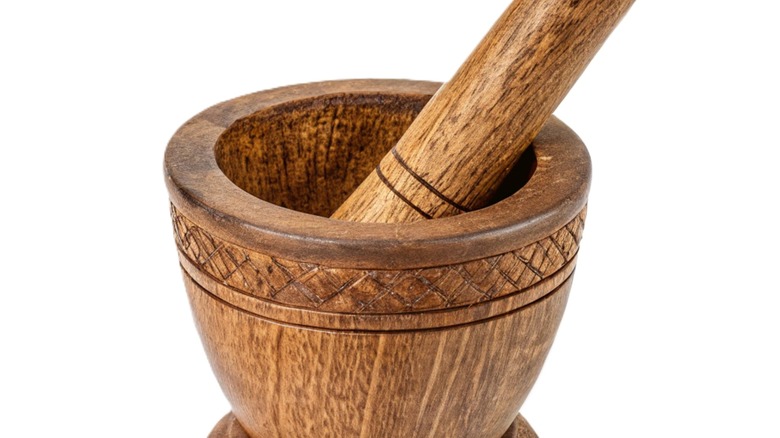 Traditional wooden mortar and pestle kitchen tool isolated on white background.