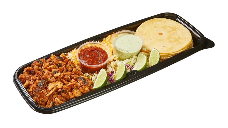 A black plastic tray holding the ingredients for chicken tacos