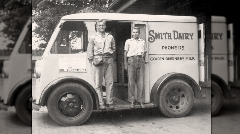 Two men posing on a Smith Dairy truck in a black and white photo